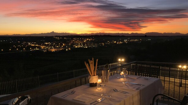 A table set for dining with a view of a cityscape at sunset.