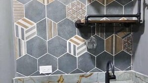 Una cocina con lavavajillas incorporado, un fregadero y un salpicadero con diseños geométricos de azulejos.