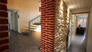 Un interior amplio con una escalera, un pilar de ladrillo y un muro con textura.