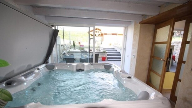 Un jacuzzi en una habitación con puerta de vidrio que da al exterior.