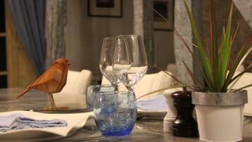 Een tafel met een vogeltje, een glazen schaal met water en een bloempot met plant.