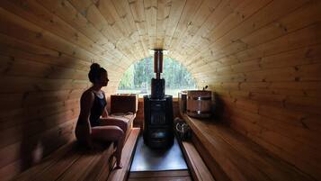 Relax in a serene sauna room with a central heater, wooden bench, and natural light from the windows.