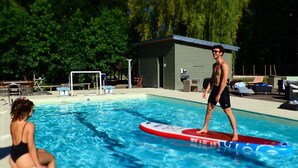 Une piscine avec un poste de surveillance pour le sauveteur, un petit bâtiment et des arbres en arrière-plan.