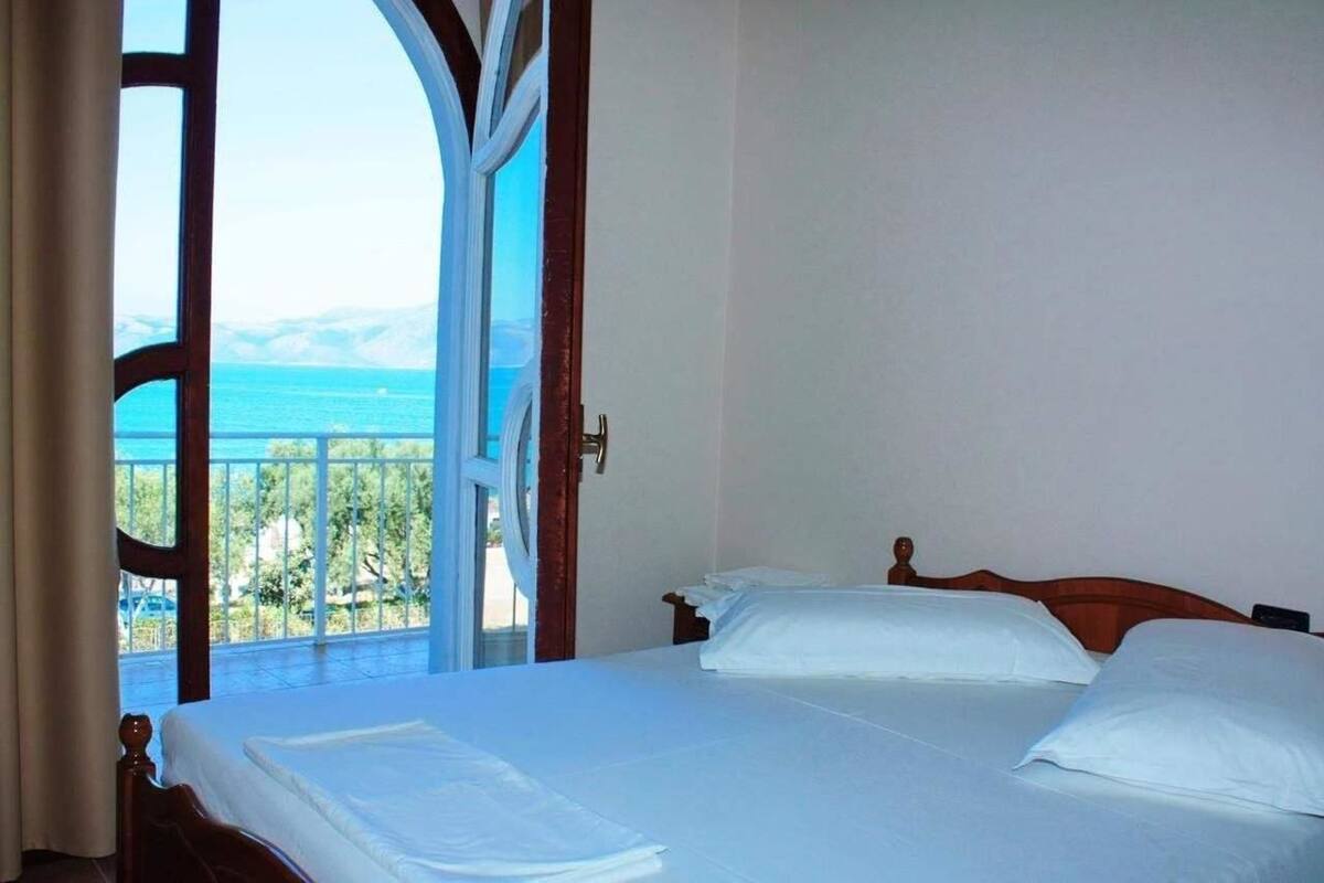 A bedroom with a bed, a window, and a view of the sea.