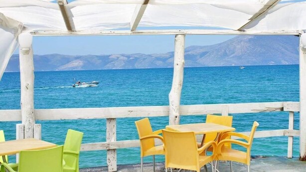 Un espace extérieur abrité, aménagé avec des sièges, et offrant une vue sur la mer et les montagnes.