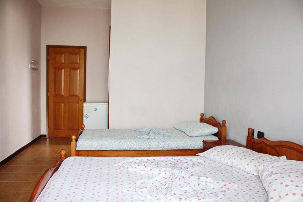 A bedroom with two beds, a wooden door, and a white wall.