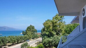 Une propriété située sur la côte, offrant une vue sur la mer, une route et un bâtiment doté d’un balcon.