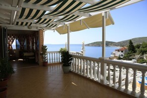 A balcony with a view of the sea, a potted plant, and a dining area with chairs and a table. - Qeparo Napolon Complex (Himarë)