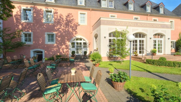 Um edifício rosa com uma placa que diz 'Gastehaus Moseikloster'.