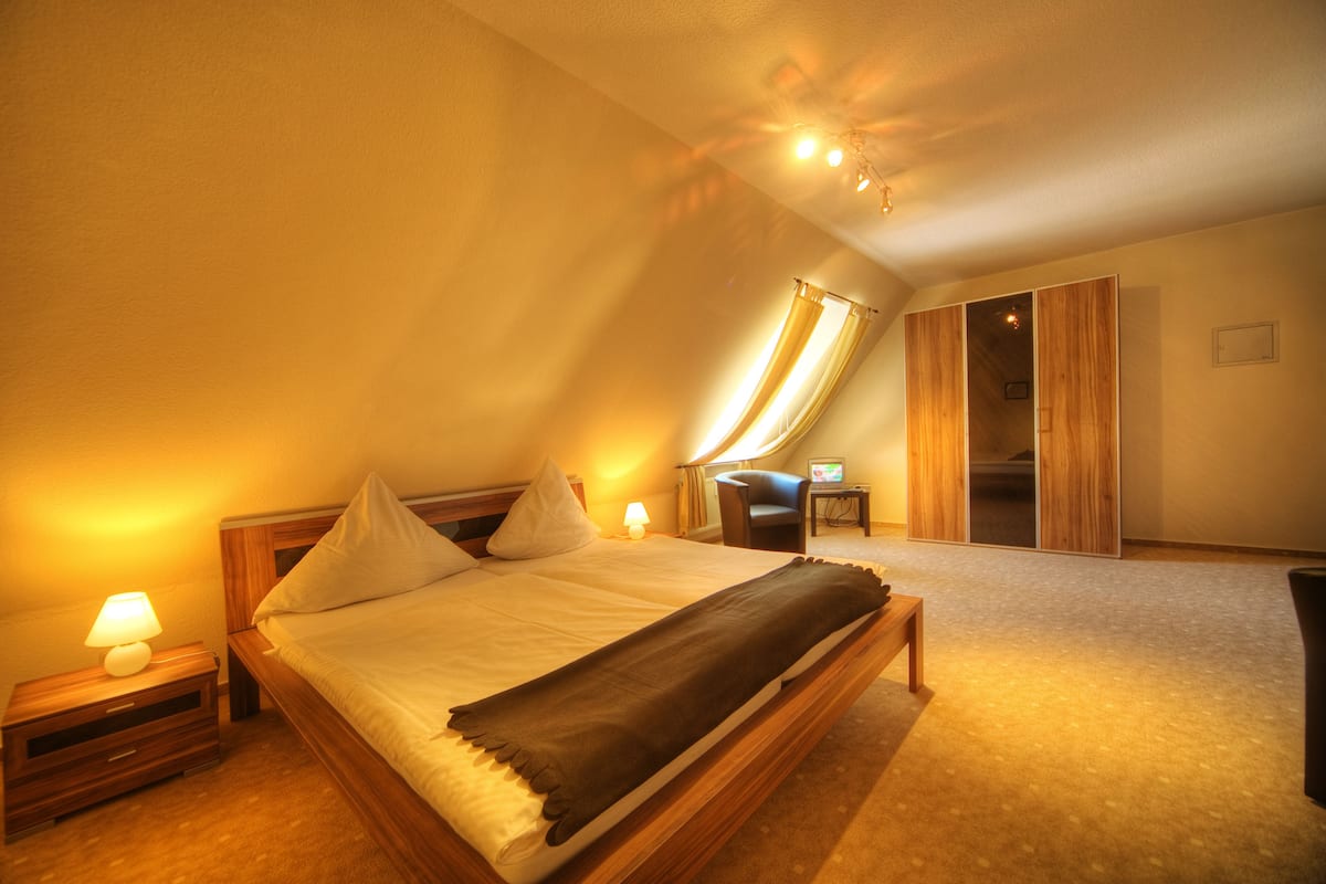 Une chambre à coucher comprenant un lit, des tables de chevet, une chaise et une armoire.