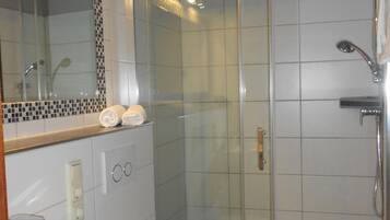A modern bathroom with a glass-enclosed shower, a white sink, and a toilet.