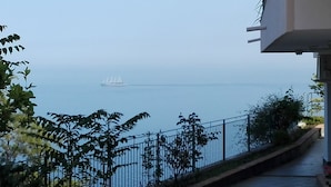 A coastal view with a white sailboat on the water, a metal railing, and greenery. - La nave sul mare di Taormina B&B (Letojanni)