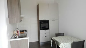 Una cocina compacta con lavabo, estufa, horno y una zona de comedor con mesa y sillas.