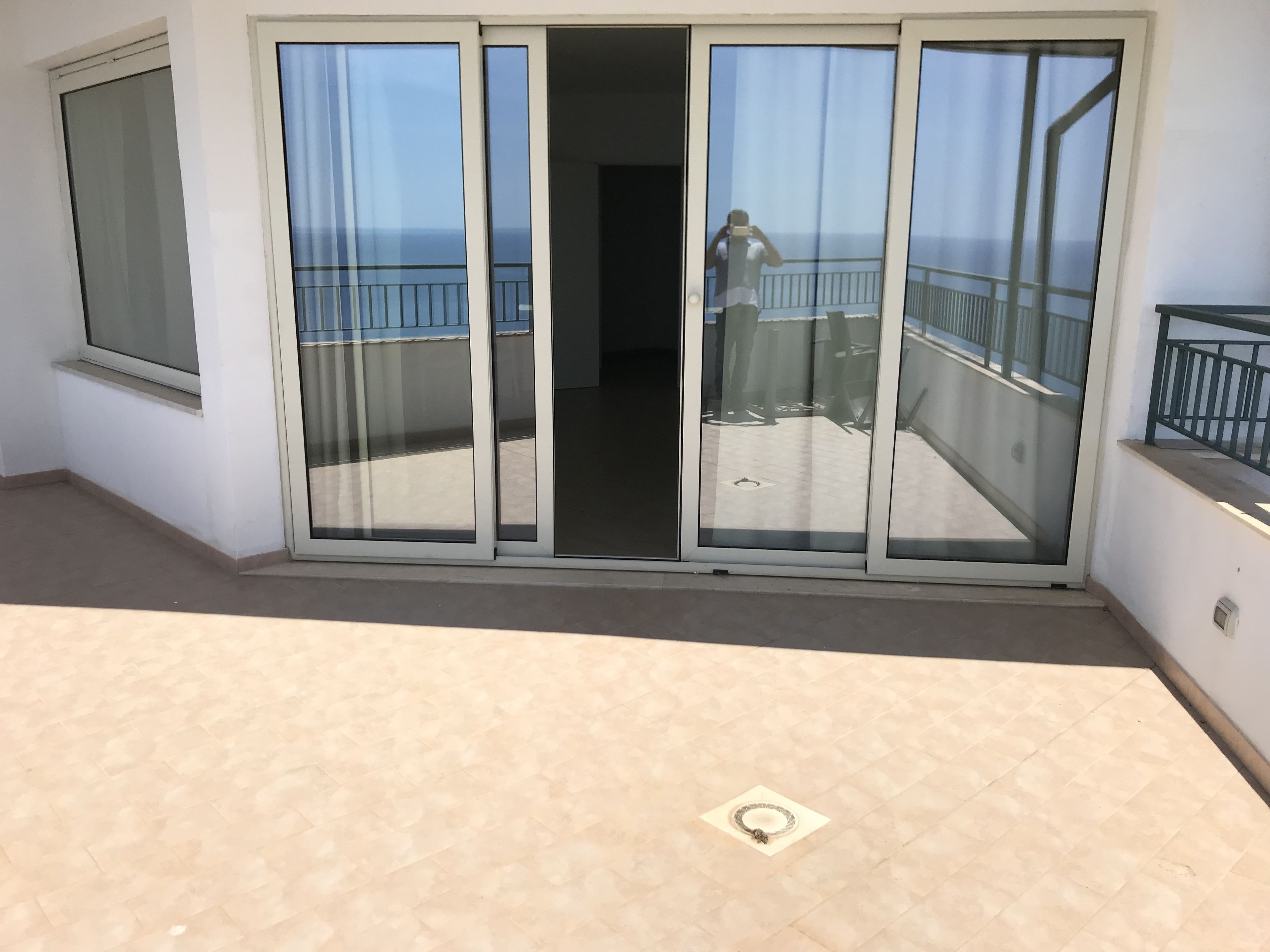 Un balcon doté d’une porte vitrée donnant sur une terrasse avec vue sur la mer.