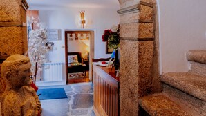 A stone archway leading to a room with a bed, a lamp, and a vase with flowers. - Dom Dinis Marvão (Marvao)