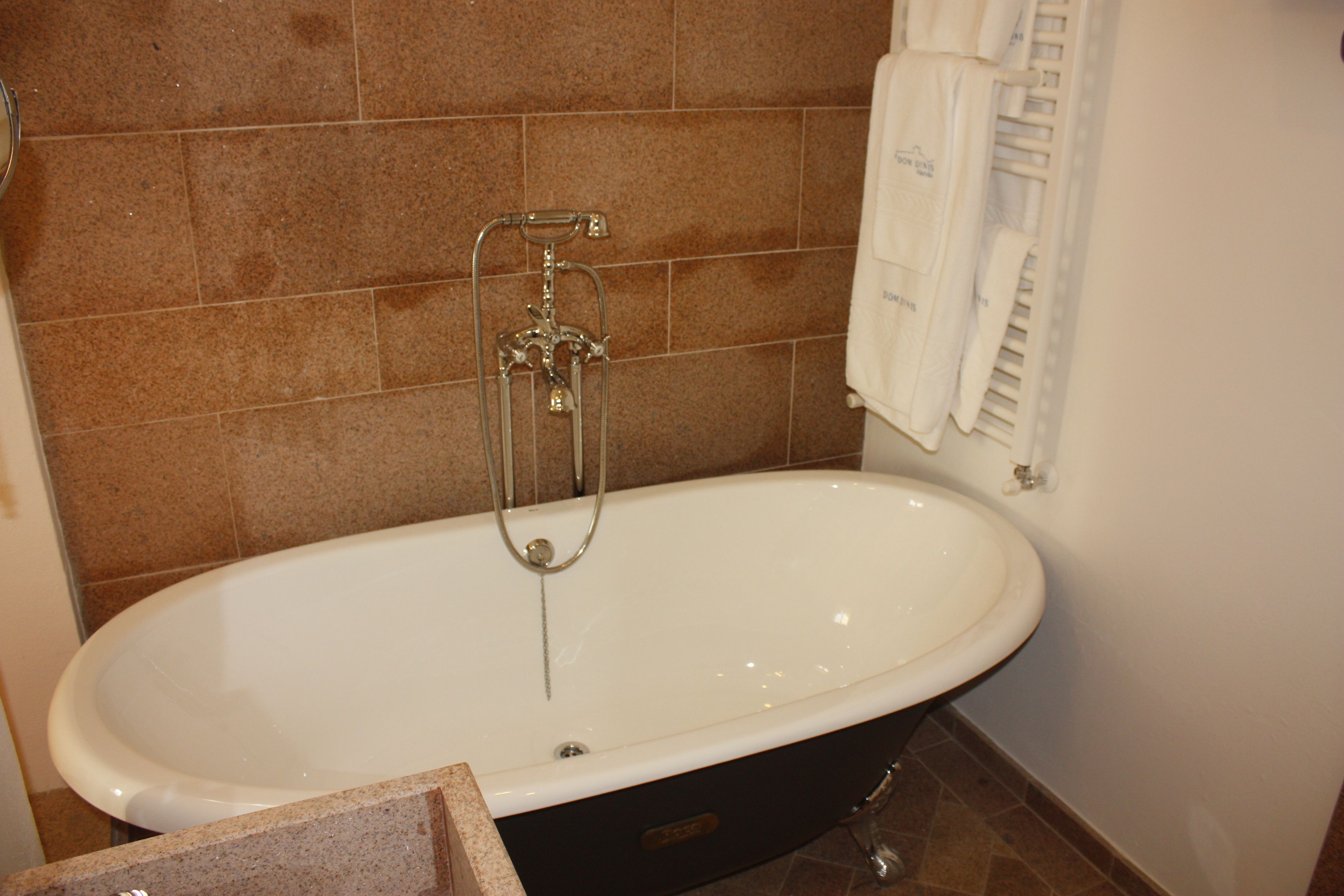 A bathroom with a freestanding bathtub, a towel rack, and a showerhead.