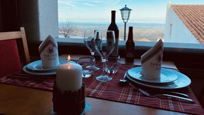 A table set for two with wine glasses, a candle, and a bottle of beer, overlooking a scenic view. - Dom Dinis Marvão (Marvao)