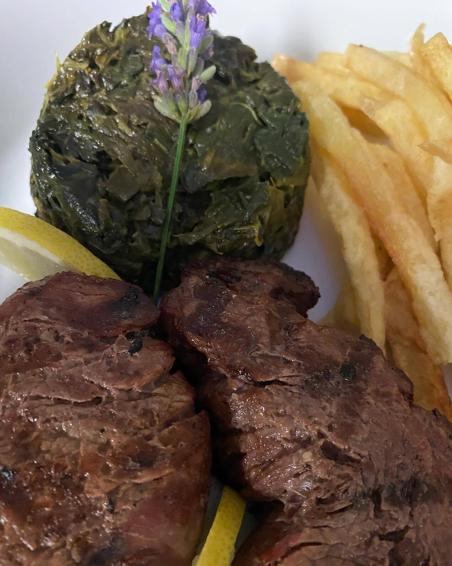 Un plato con carne a la parrilla, verdura al horno y papas fritas.