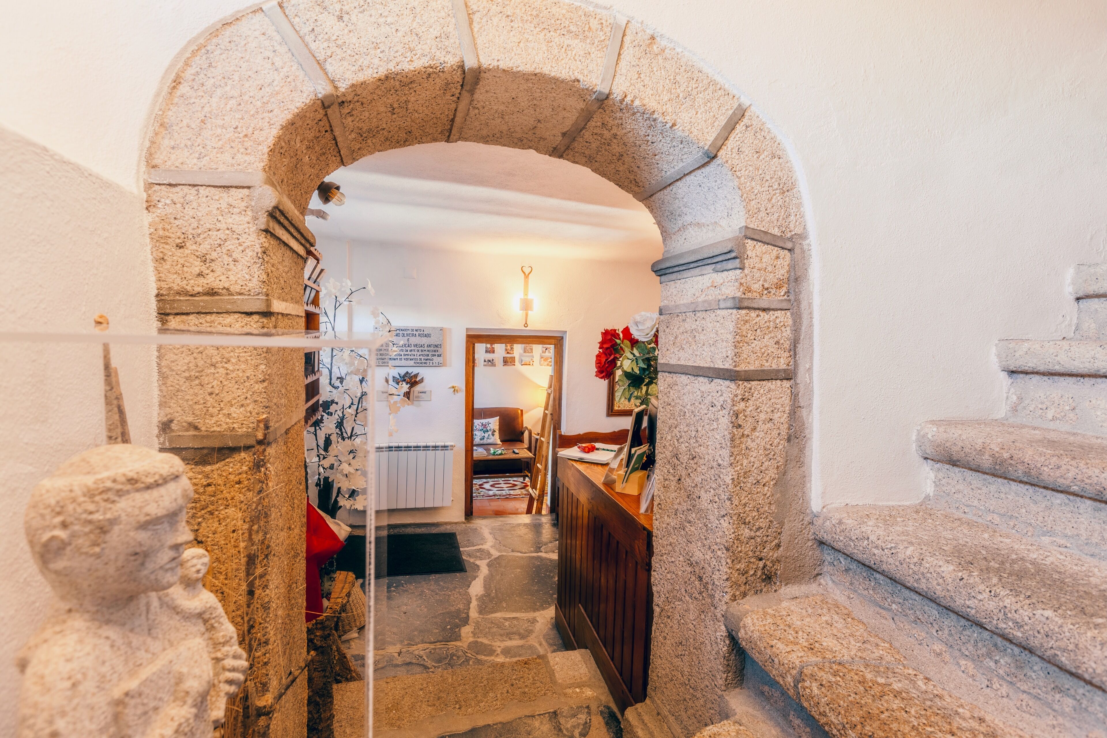 Una scala in pietra ad arco che conduce a una stanza con un letto, una scrivania e una sedia.