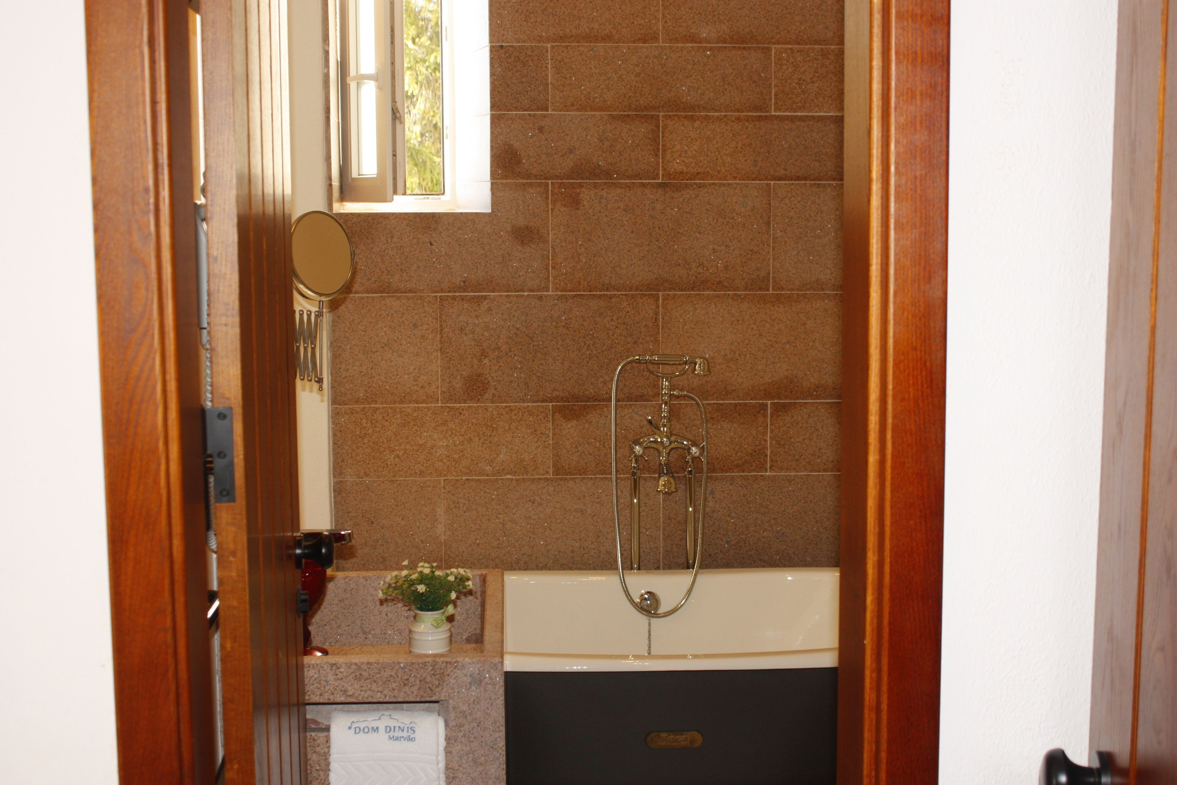 A bathroom with a bathtub, a shower, and a small window.