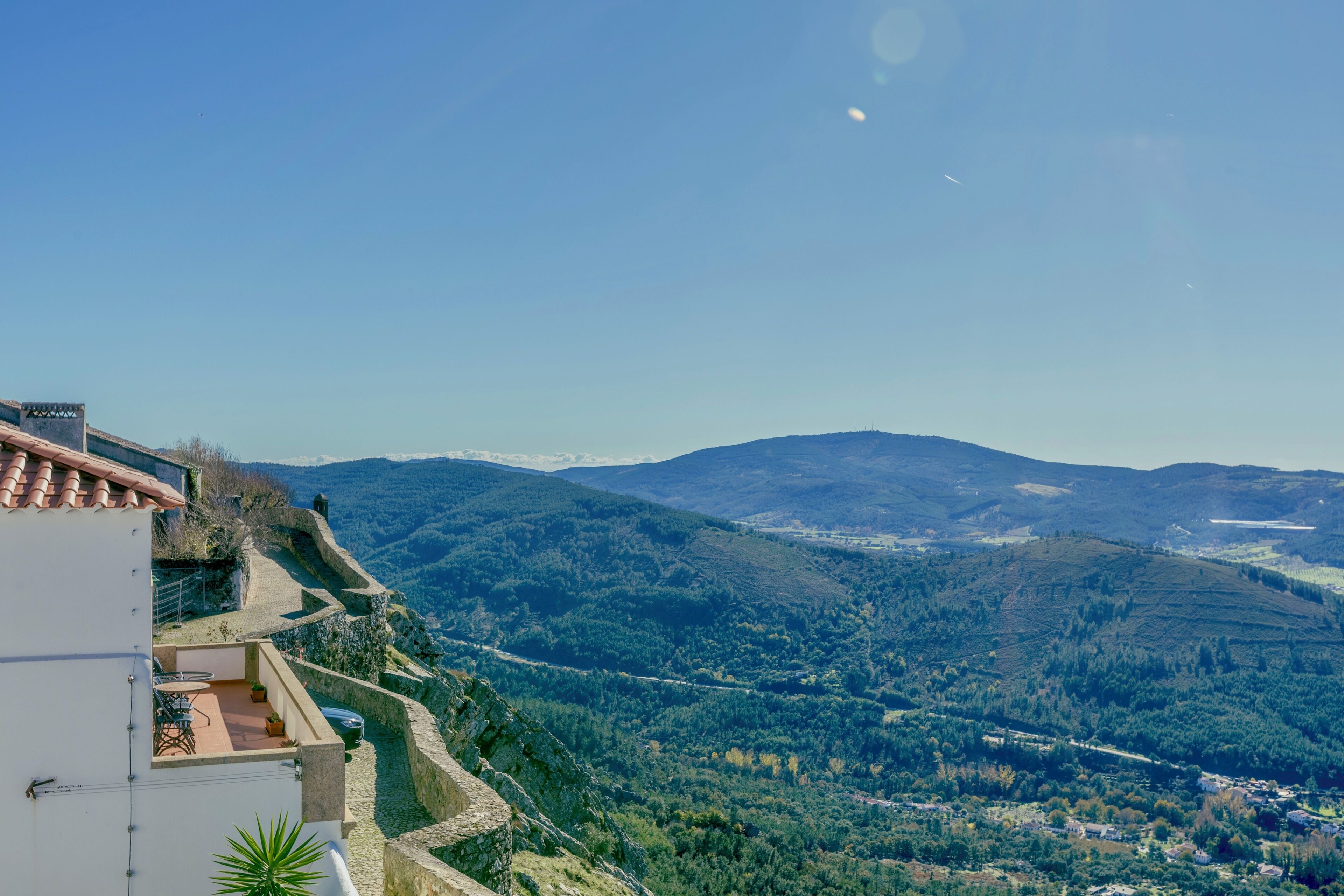 A hillside property with a terrace and a view of the surrounding hills.