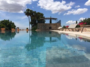 A clear pool with lounge chairs and a stone structure. - Finca Es Cabas (Santa Maria del Camí)