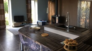 A modern kitchen with a central island, a built-in stove, and a large window providing natural light. - La Bergerie Baroque (Verrieres)
