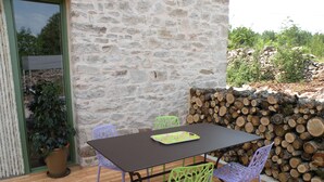 A stone wall, a table, and chairs in a patio area. - La Bergerie Baroque (Verrieres)