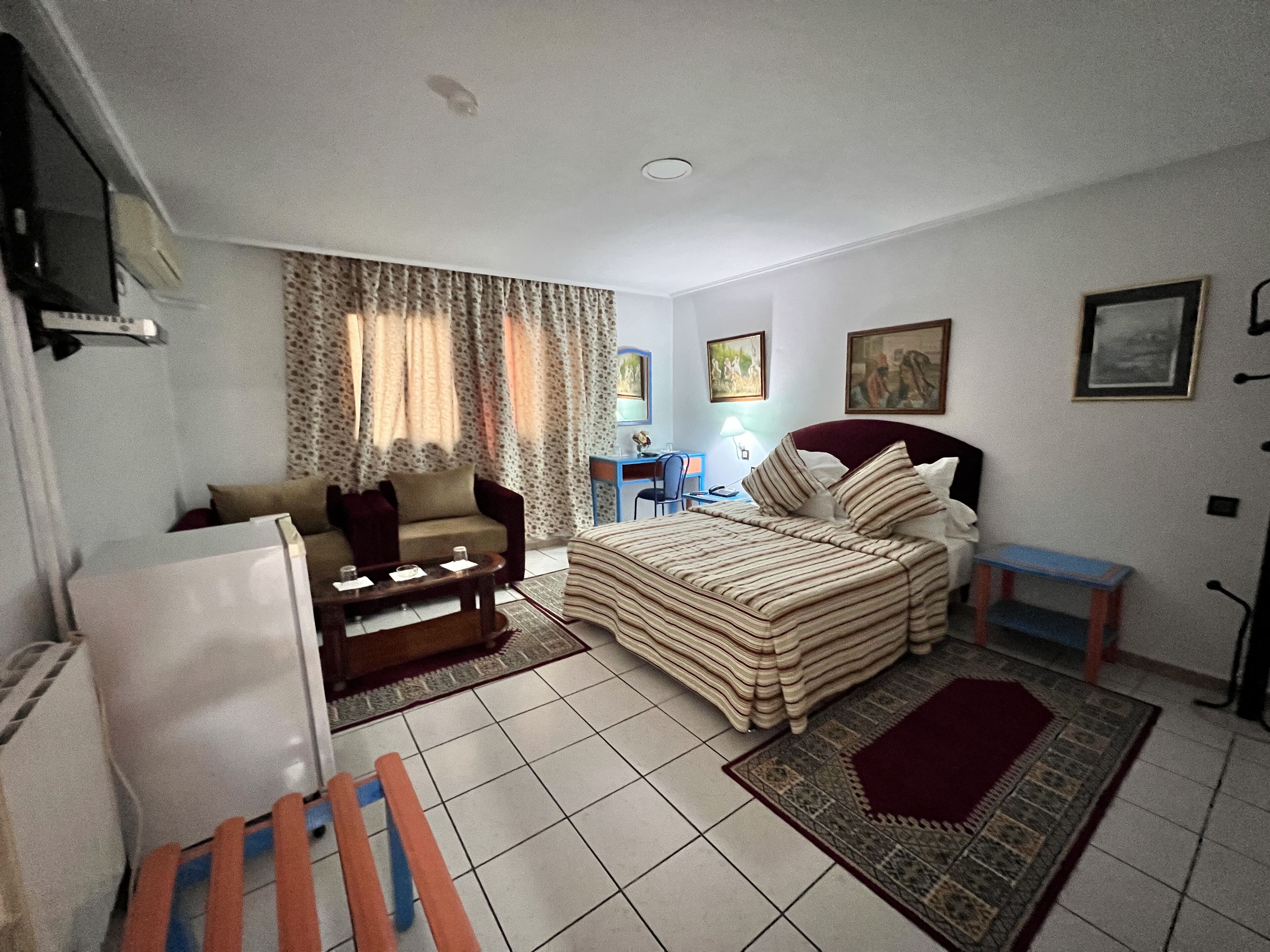 Habitación de hotel compacta con cama, sofá, escritorio y silla.