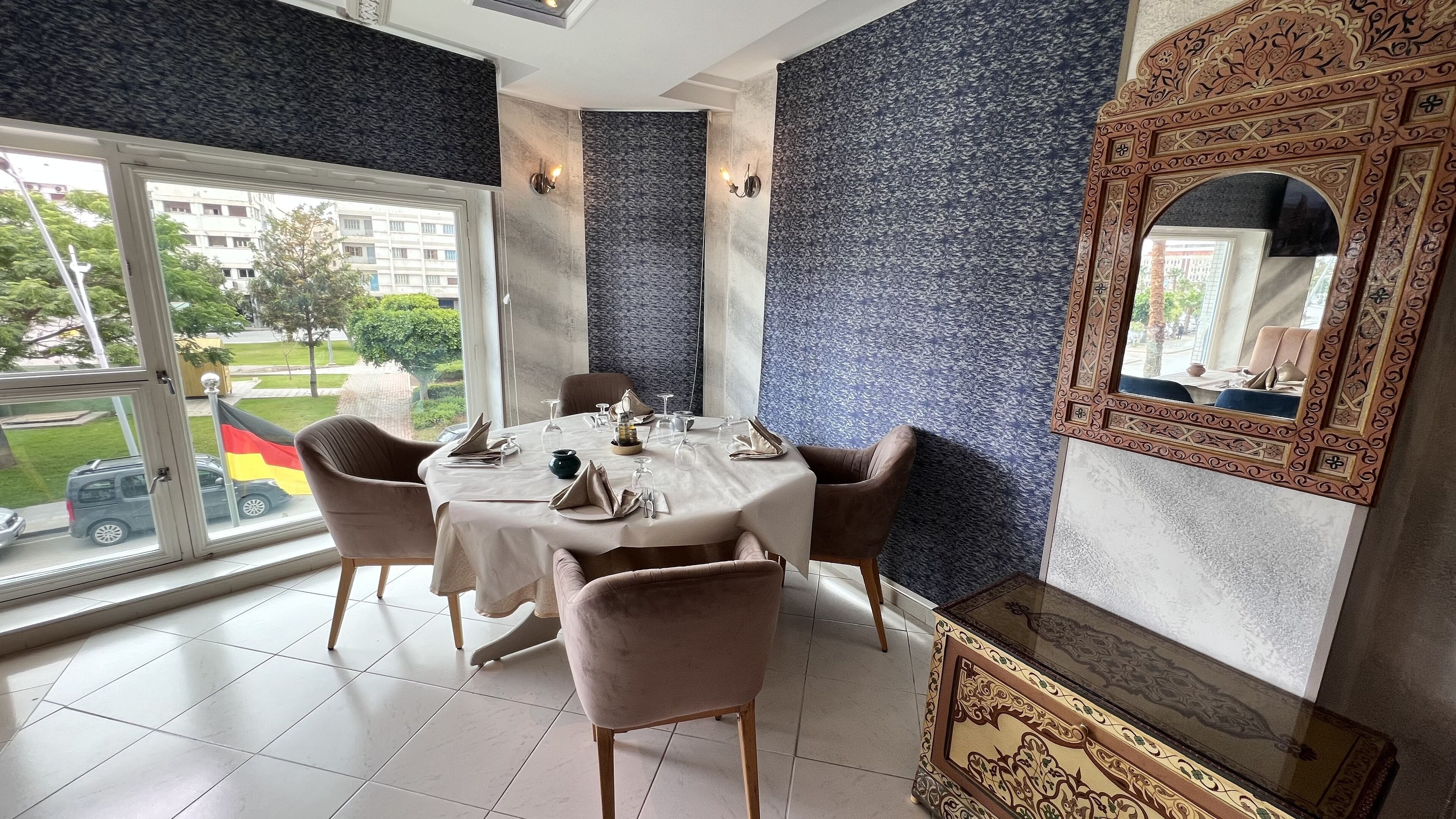A dining area with a round table set for four, surrounded by cushioned chairs.