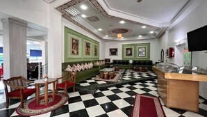 A lobby with a checkered floor, green upholstered seating, and a reception desk.