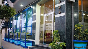 A hotel entrance with large glass doors, potted plants, and a sign reading "ANNAKHIL HOTEL".
