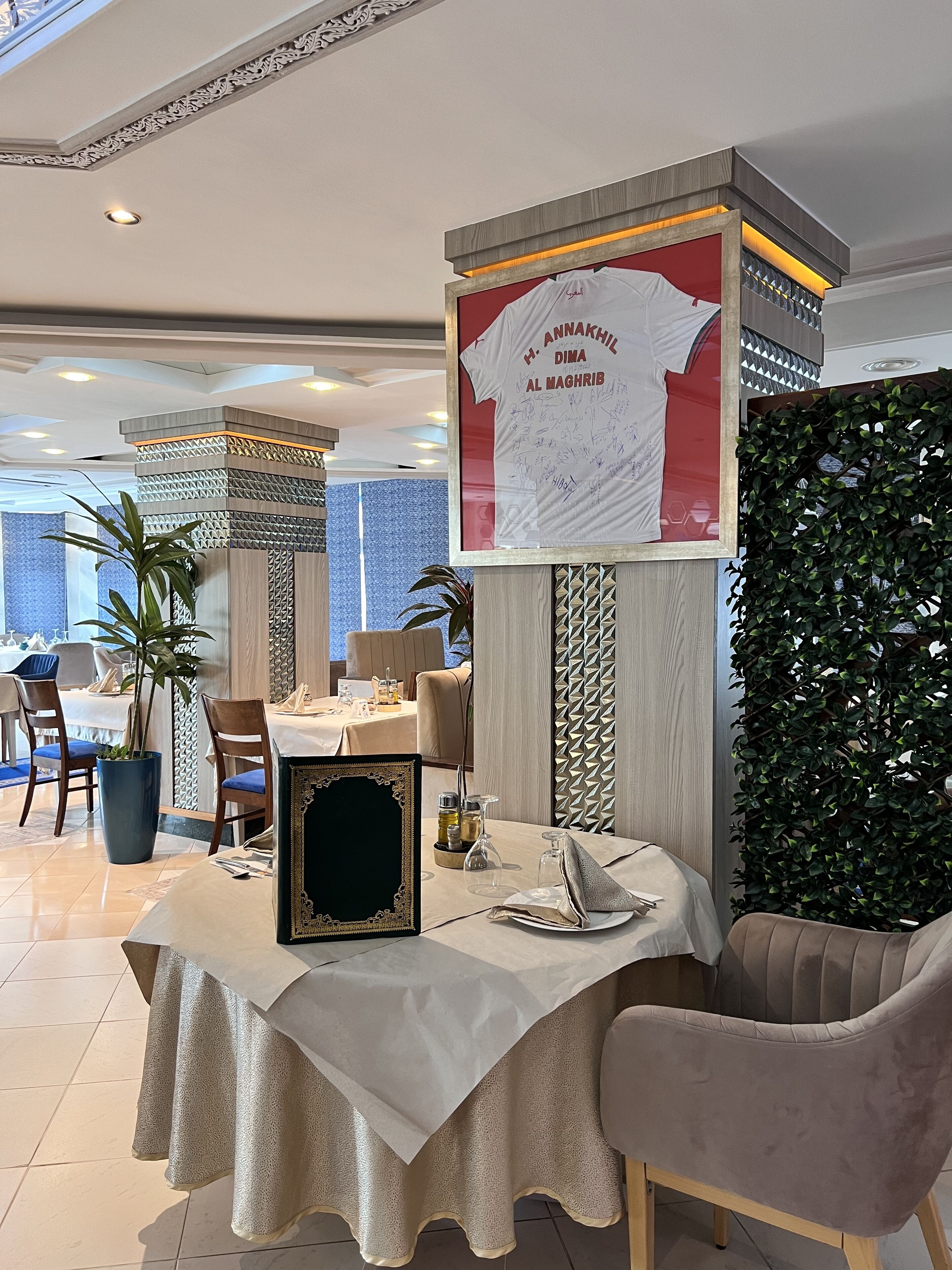 A dining area with a table set for two, a framed picture, and a decorative wall with a poster.