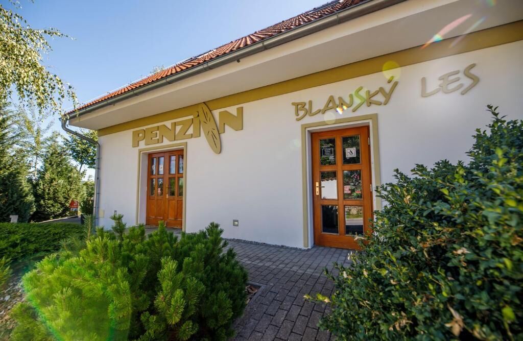 A building with the sign "PENZAN BLANKY LES" and two wooden doors.