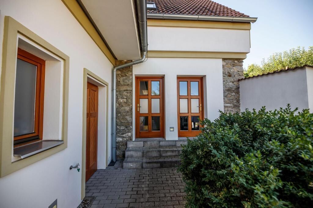 Ein zweistöckiges Haus mit einer Steinaußenwand, zwei Holztüren und einem Ziegelweg, der zum Eingang führt.