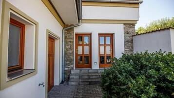 Ein zweistöckiges Haus mit einer Steinaußenwand, zwei Holztüren und einem Ziegelweg, der zum Eingang führt.