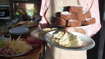 Uma pessoa na cozinha segurando um prato com pão e uma cesta com alimentos.