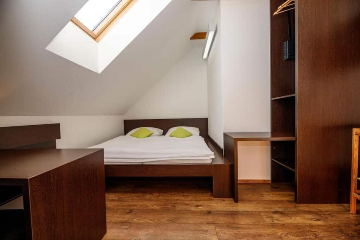 Quarto com claraboia, cama, mesa de cabeceira e guarda-roupa.