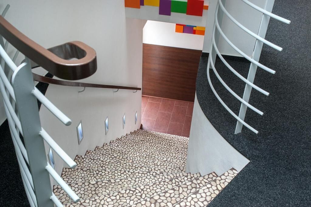Een moderne trap met een uniek ontwerp, met een patroon vloer en een houten leuning.