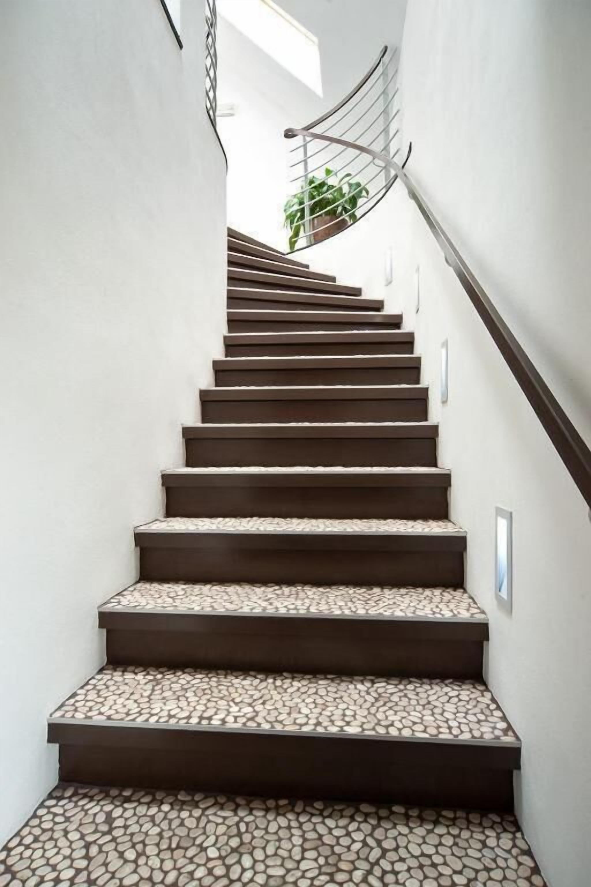 A staircase with a unique pebble-patterned floor and a metal spiral railing.