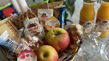 A fruit bowl with apples, bread, and various packaged snacks.