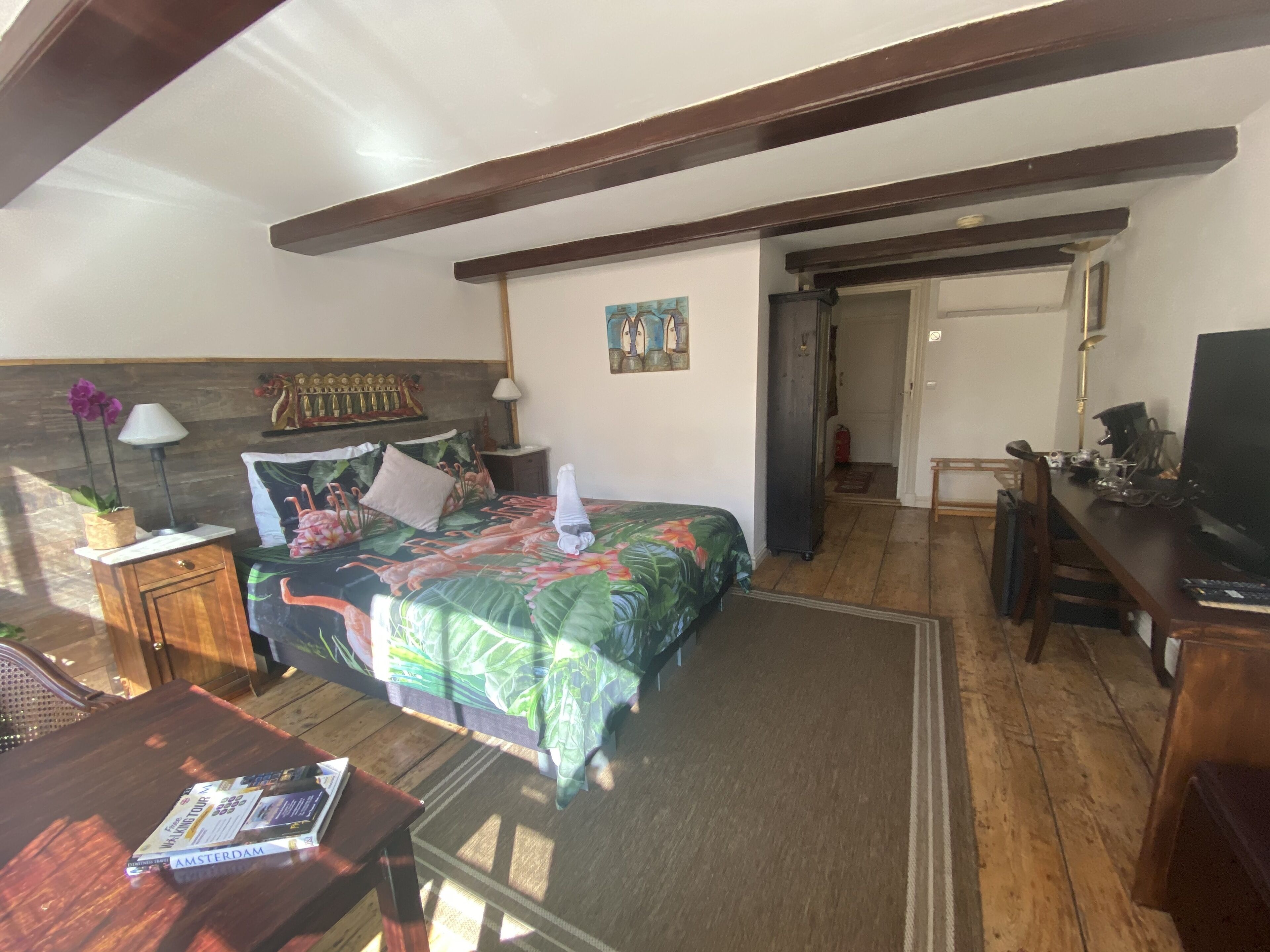 A bedroom with a bed, a desk, a chair, a lamp, and a TV.