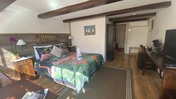 A bedroom with a bed, a desk, a chair, a lamp, and a TV.