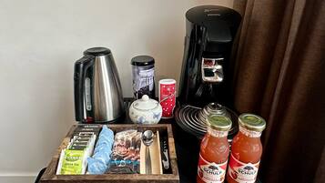 Una estación de café con una cafetera, tetera y diferentes cápsulas de café.
