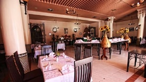 A spacious dining area with multiple tables set for guests, featuring classic chandeliers and a warm, inviting atmosphere. - Hotel Club Hanane (Ouarzazate)