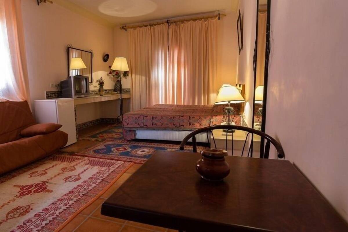 Un salon chaleureux avec un canapé, une petite table sur laquelle est posé un vase, et un tapis à motifs.