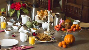 A breakfast table with various food items, a coffee pot, a thermos, and a candle.