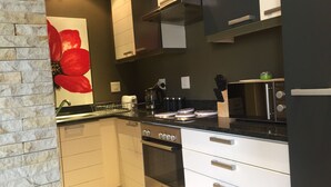 A modern kitchen with white cabinets, a stainless steel oven, and a black countertop. - Cape Town Apartment with balcony (Cape Town)