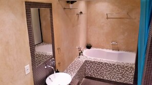 A bathroom with a bathtub, a sink, and a mirror. - Cape Town Apartment with balcony (Cape Town)