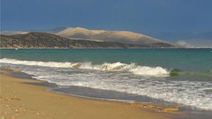 A beach with waves, a clear sky, and distant mountains. - Porto Assini (Nafplio)